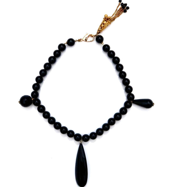 Black bead necklace with different shape pendents and a fringe bell at clasp