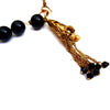 Black bead necklace with different shape pendents and a fringe bell at clasp